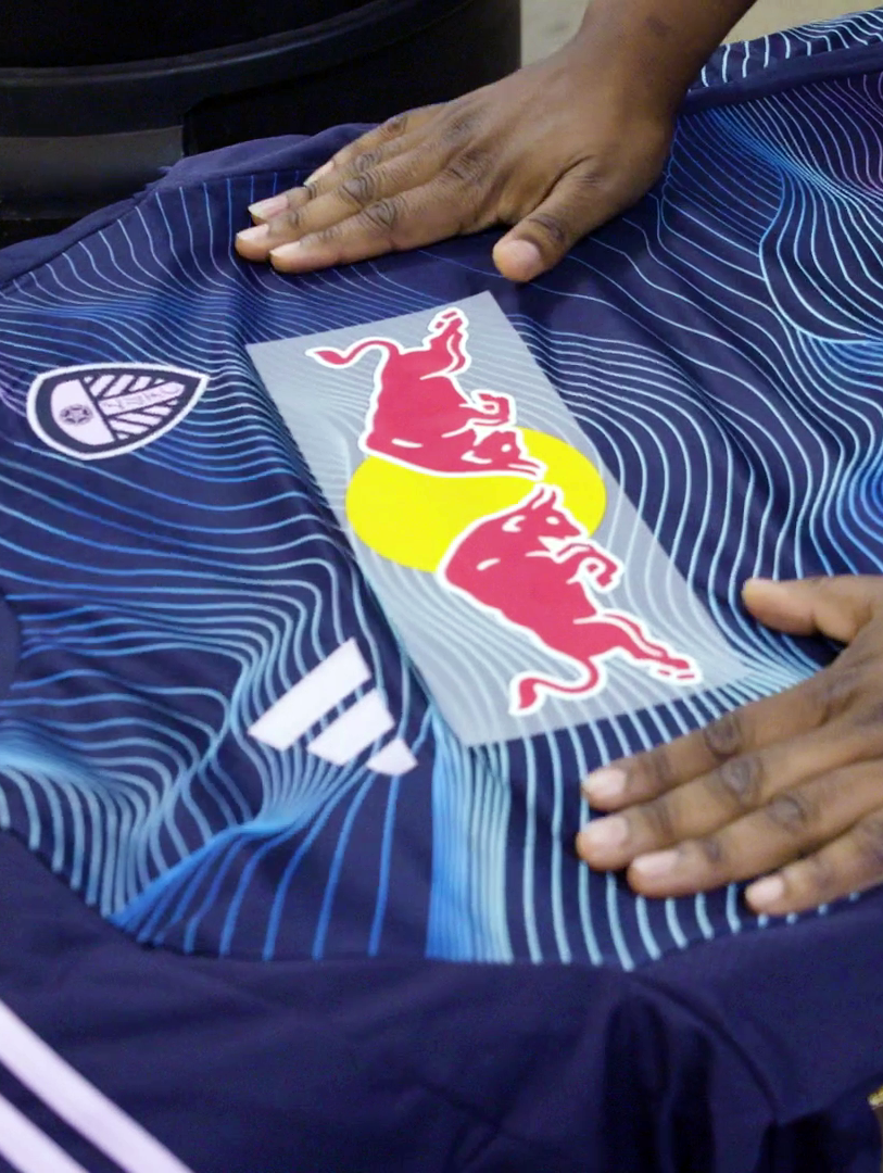 Image showing a Red Bull sponsor embellishment being added to a jersey